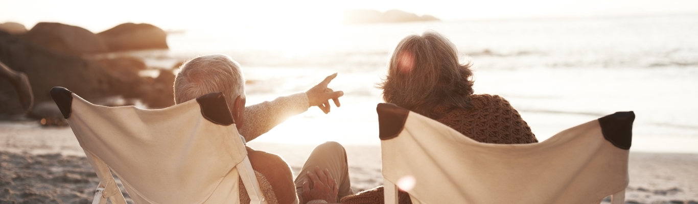 Mature couple sitting on beach chairs looking at ocean